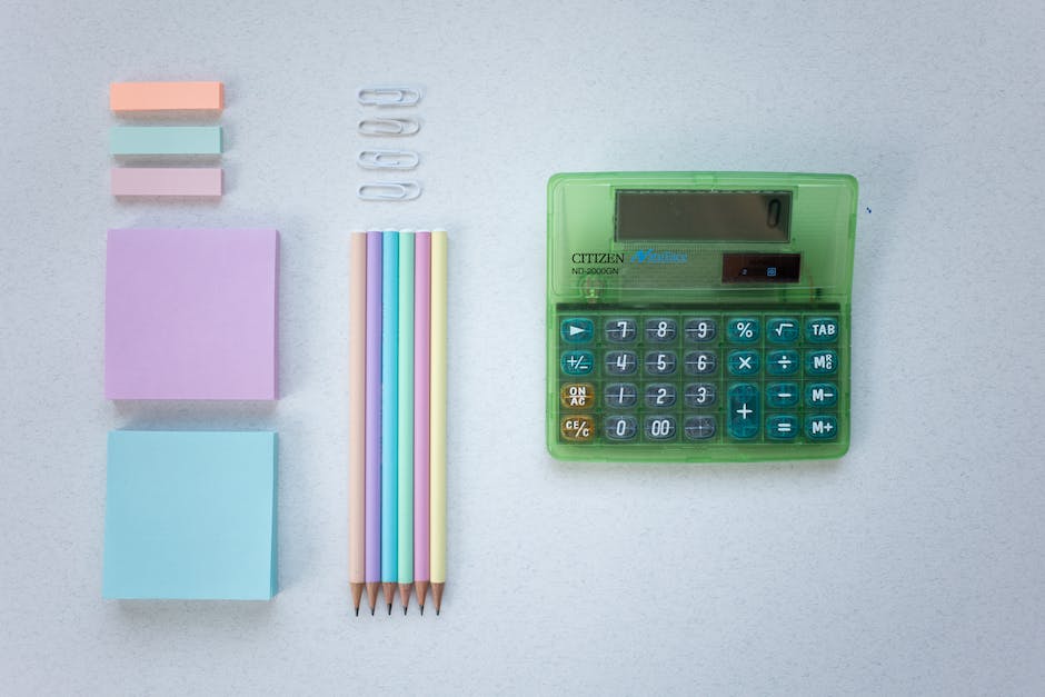 A calculator on a table next to a journal and pen, representing using compound interest to save money