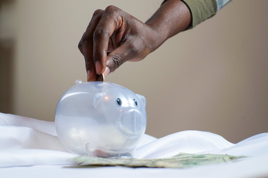 Picture of a person putting money into a piggy bank.
