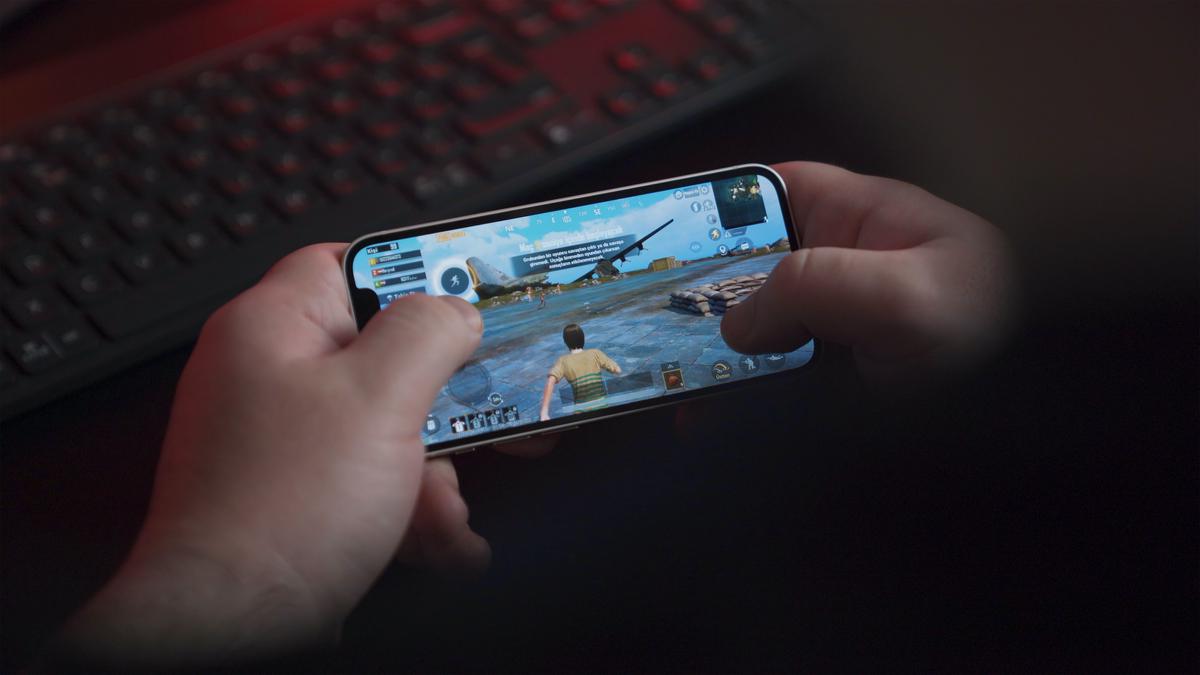 Image of a person playing a mobile game on a smartphone with a dramatic background showing the growth of the mobile gaming market.