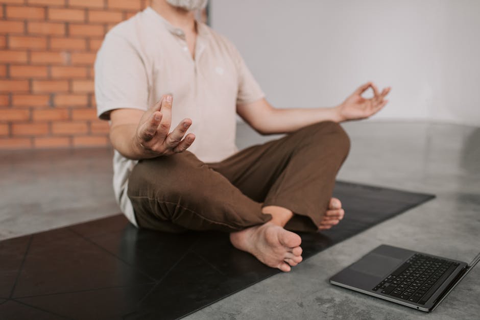 A person meditating with a laptop on a trading floor