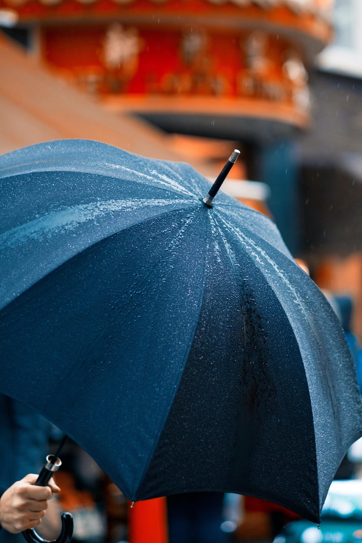 A person holding an umbrella in a storm, symbolizing the need to prepare for a recession.