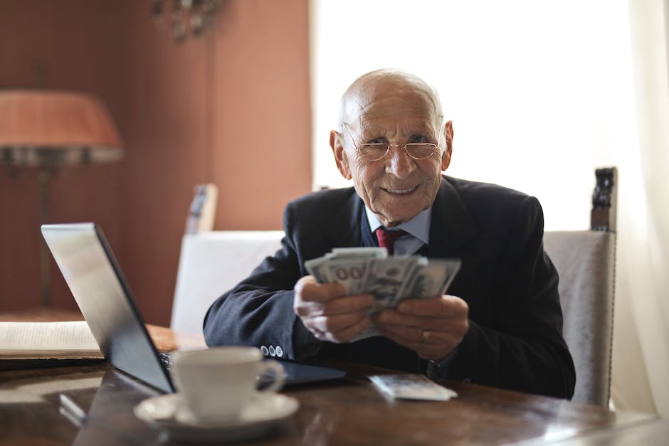 Image of an elderly person sitting in front of a computer, managing retirement investments on a website