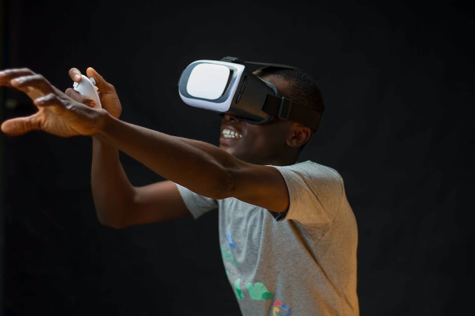 An image showing virtual reality goggles and a hand reaching towards them.